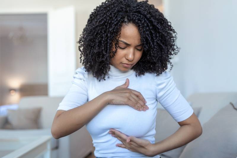 Woman palpating her breast for preventive care Woman palpating her breast for preventive care